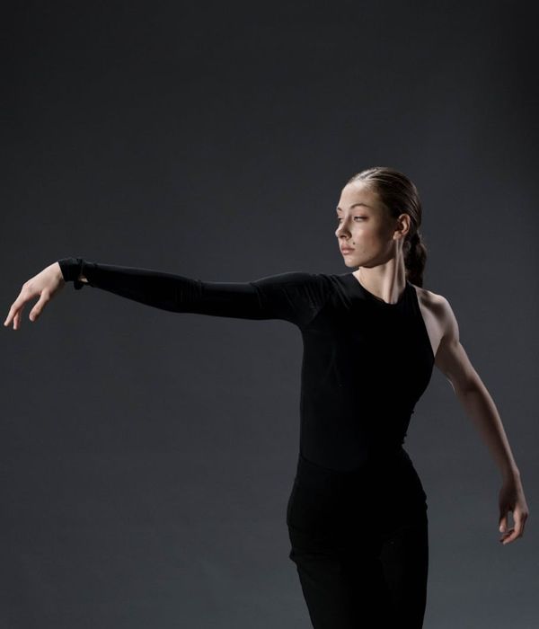 Woman in activewear performing a fluid cardio movement in a minimalist studio.